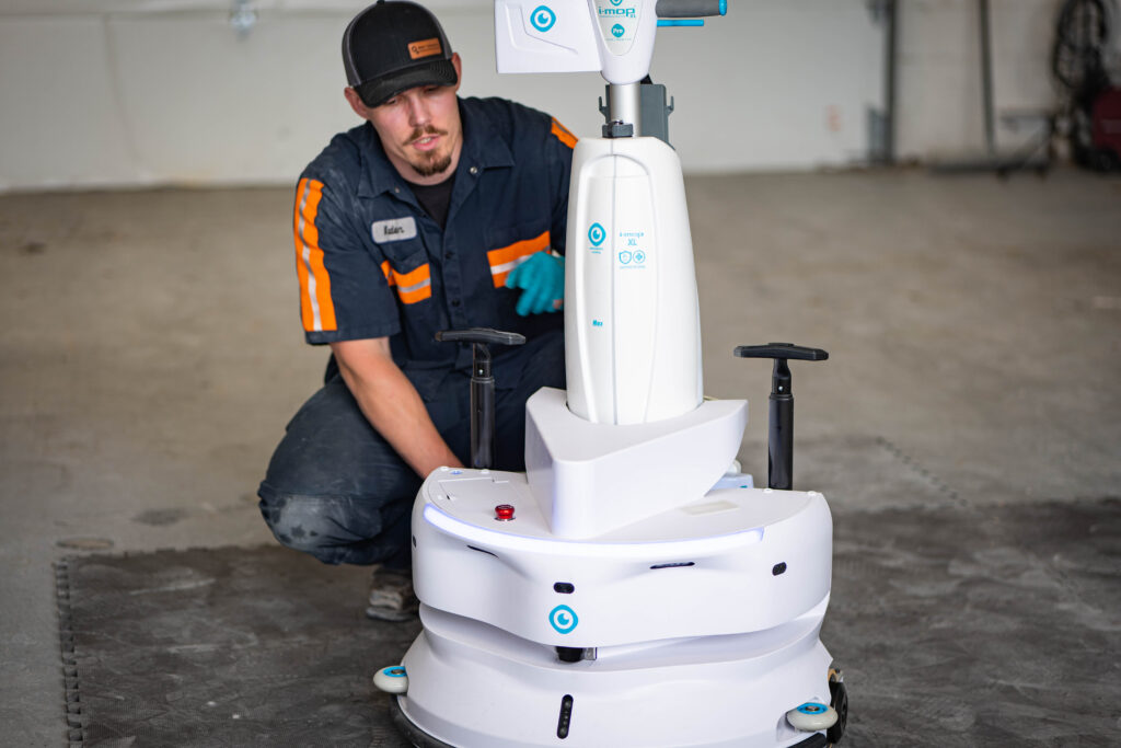 A professional WaySolutions technician inspects an advanced i-mop XL autonomous robotic floor scrubber during a maintenance check in Layton.